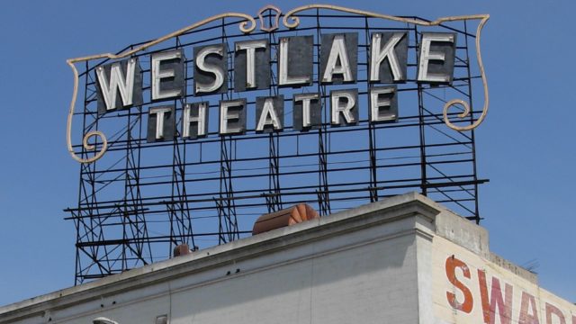 a wrought iron sign on top of a building that reads "Westlake Theatre"