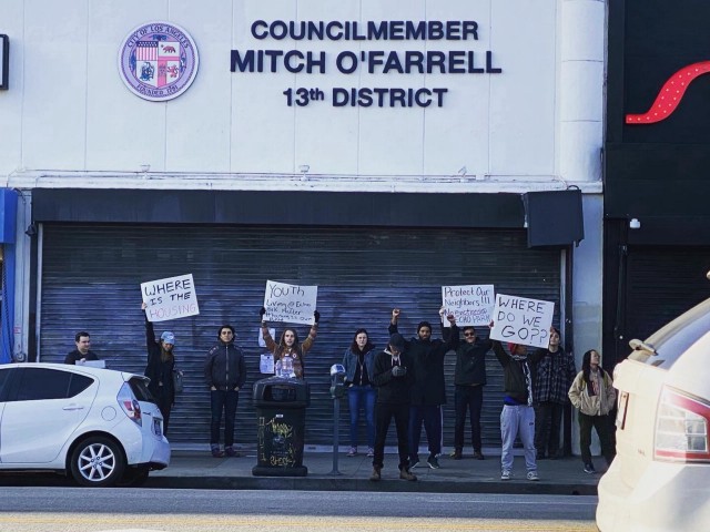 About 10 people stand with protest signs concerning housing outside of Councilmember Mitch O'Farrell's office in Los Angeles District 13.