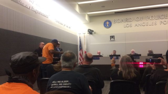 pete white, a black man wearing a bright orange shirt, addresses the LAPRD board of commissioners and resigning LAPD Chief Charlie Beck