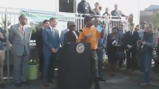general dogon - a black activist - refuses an award as mayor eric garcetti looks on while standing behind a podium