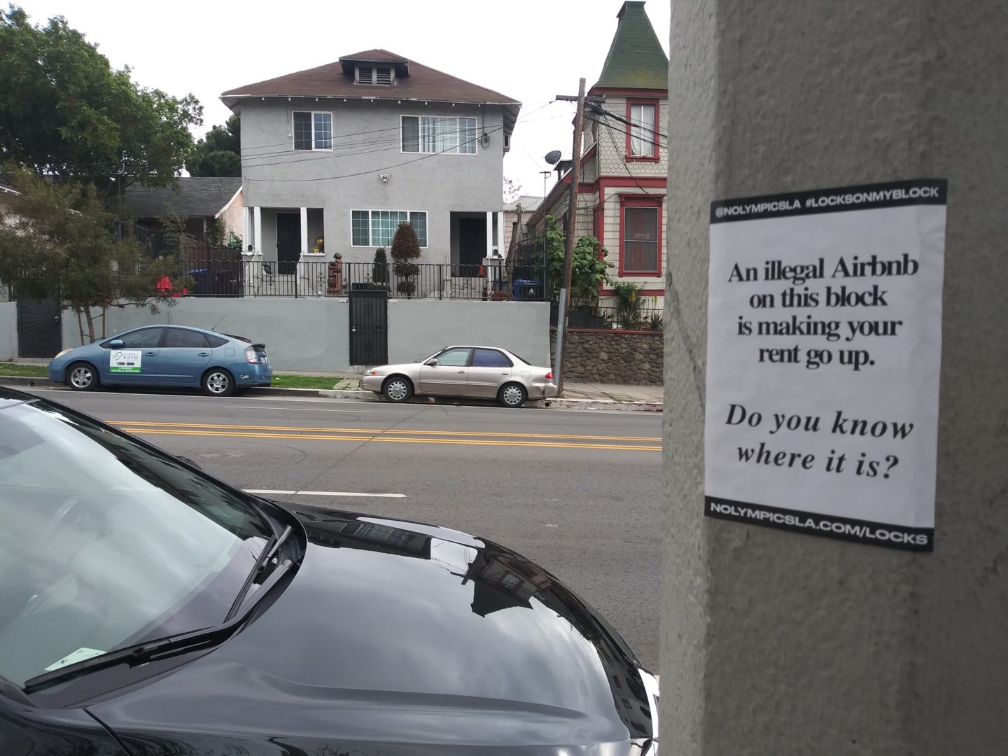 A sign reads "An illegal Airbnb on this block is making your rent go up. Do you know where it is?" 