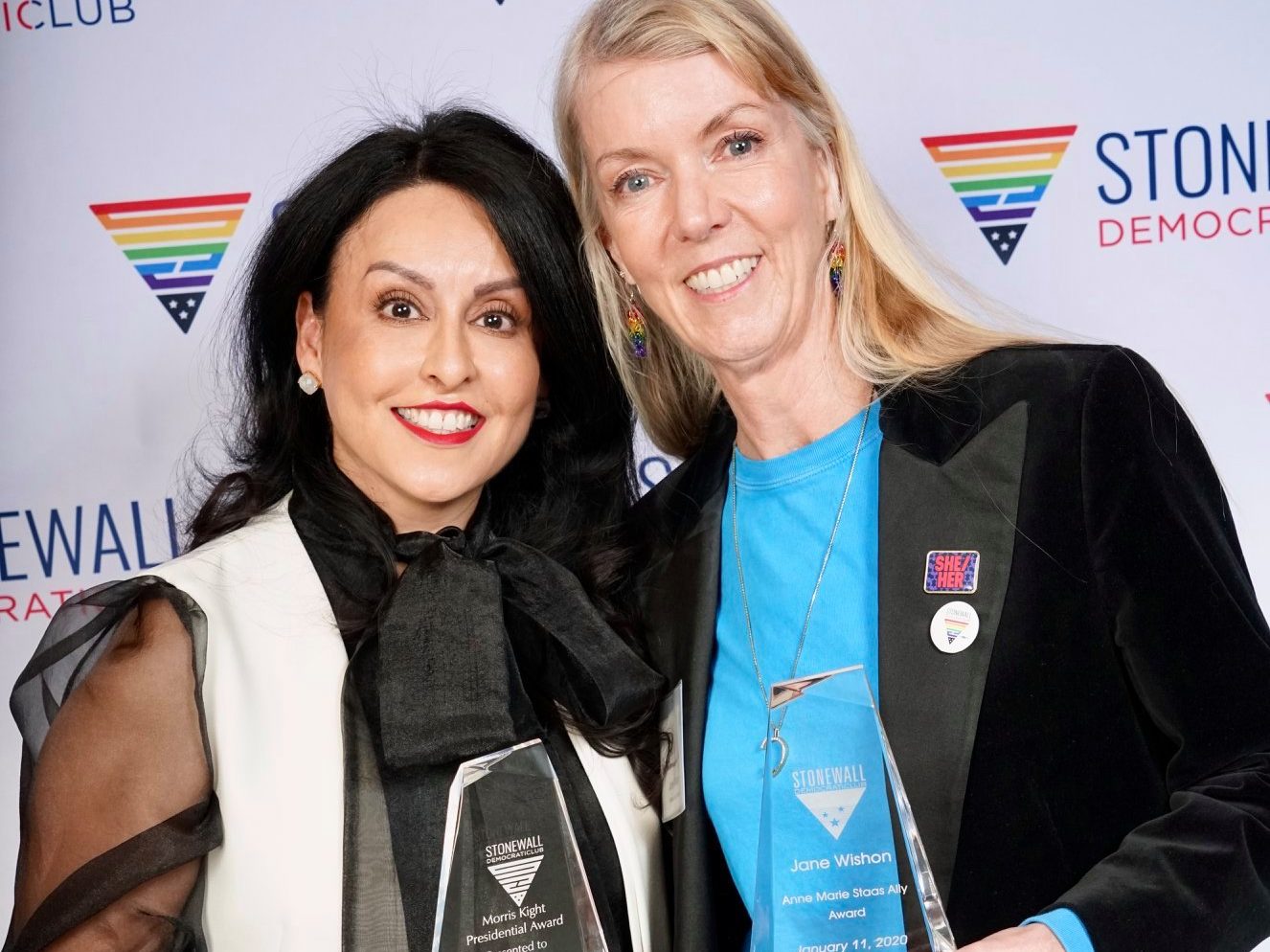 Jane Wishon and Nury Martinez pose in front of a white backdrop with awards from the Stonewall Democractic Club's "Stoney Awards"