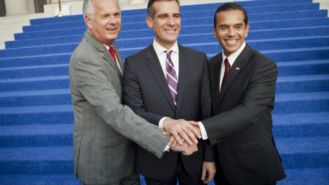 Eric Garcetti (center) poses with the two previous mayors, Antonio Villaraigosa (right) and Jim Hahn (left), at his 2013 inauguration in front of city hall steps covered in blue carpet.
