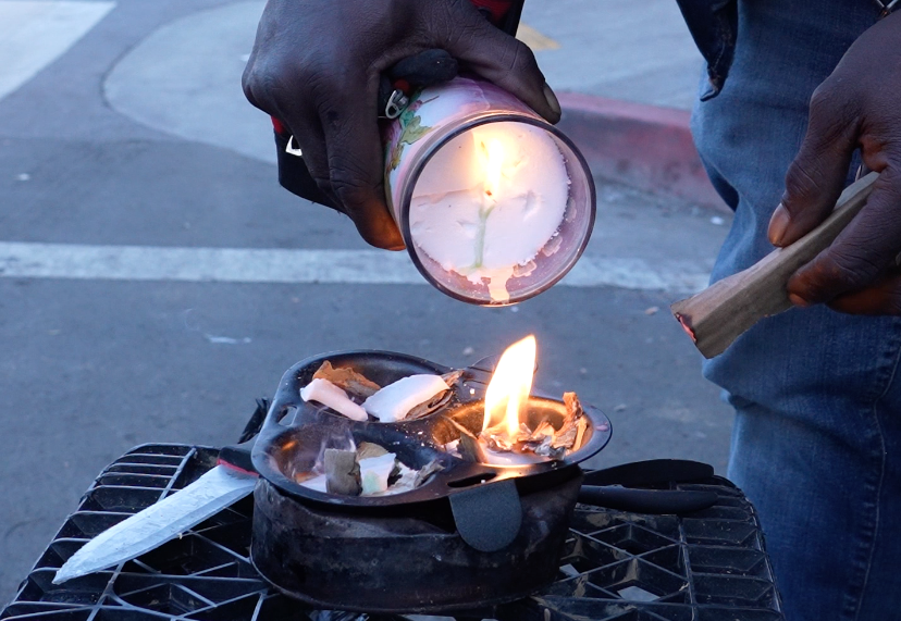 pouring a lit candle onto shaved woodchips in three metal tins