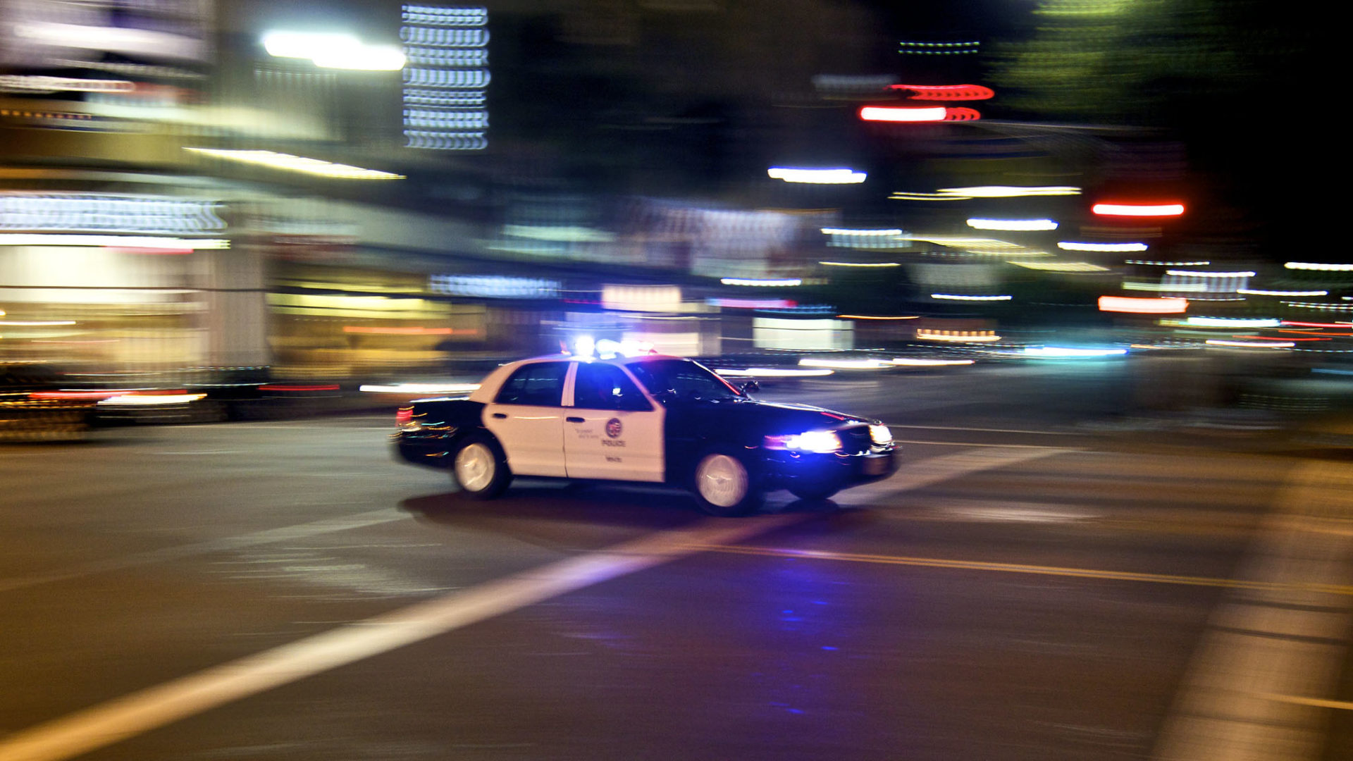 A Los Angeles Police Department vehicle drives down Sunset Boulevard with sirens flashing.