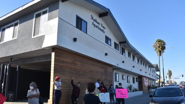 Members of the Lennox Inglewood Tenants Union hold signs outside of the Stadium View Apartments. They are part of rally on February 27, 2021.