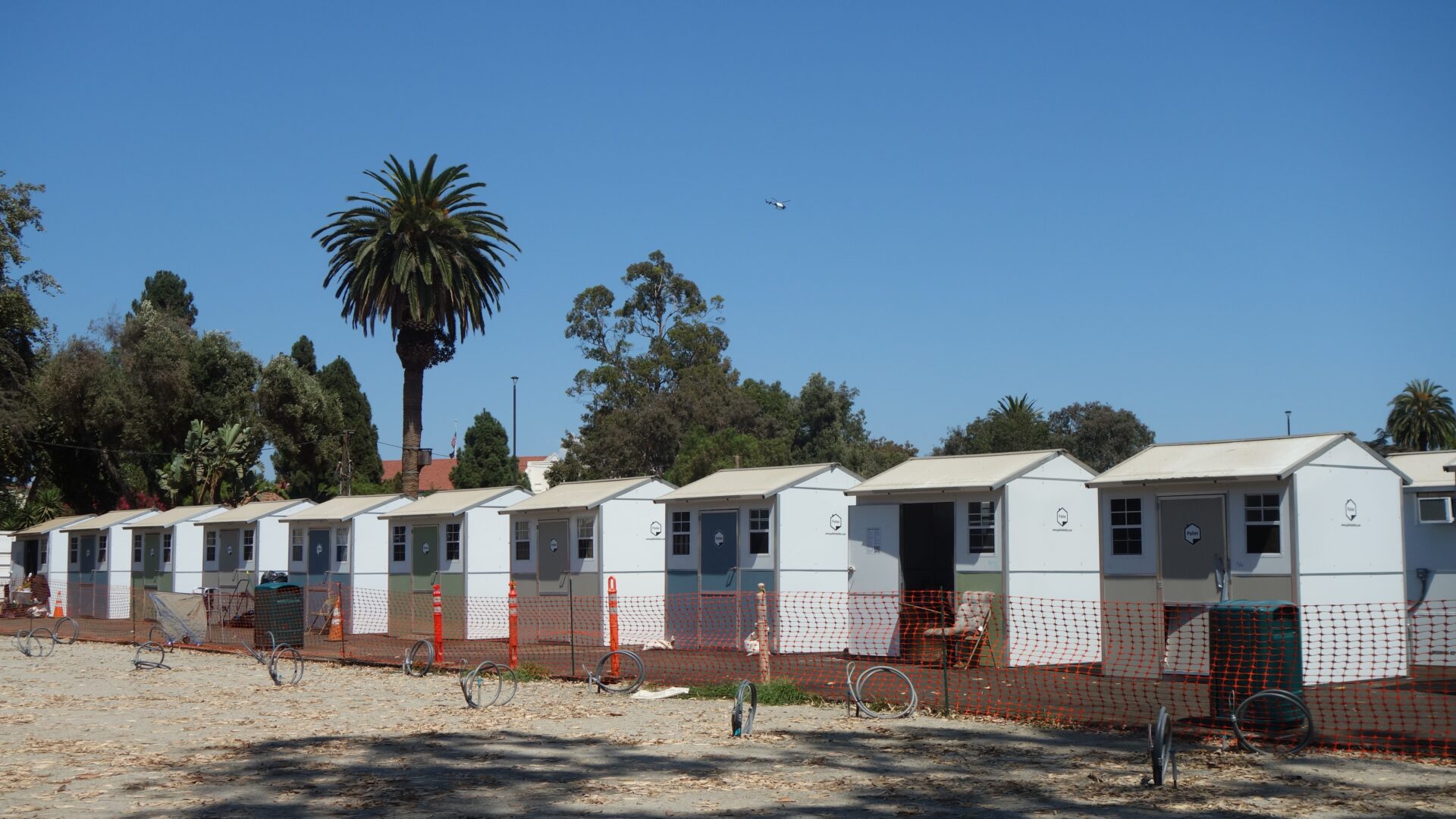 Tiny Homes in a row on the West LA VA Campus. Construction cones and a fence are in front of them.
