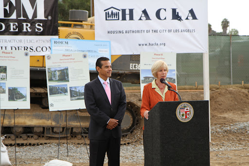 Janice Hahn stands next to then-Mayor Antonio Villaraigosa at a podium while speaking at a groundbreaking event for Phase 1 of the Dana Strand redevelopment.