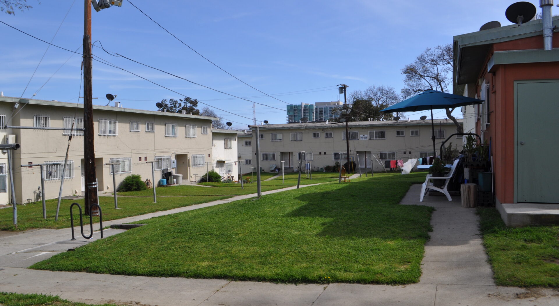 A photograph of a green lawn surrounded by two white apartment buildings